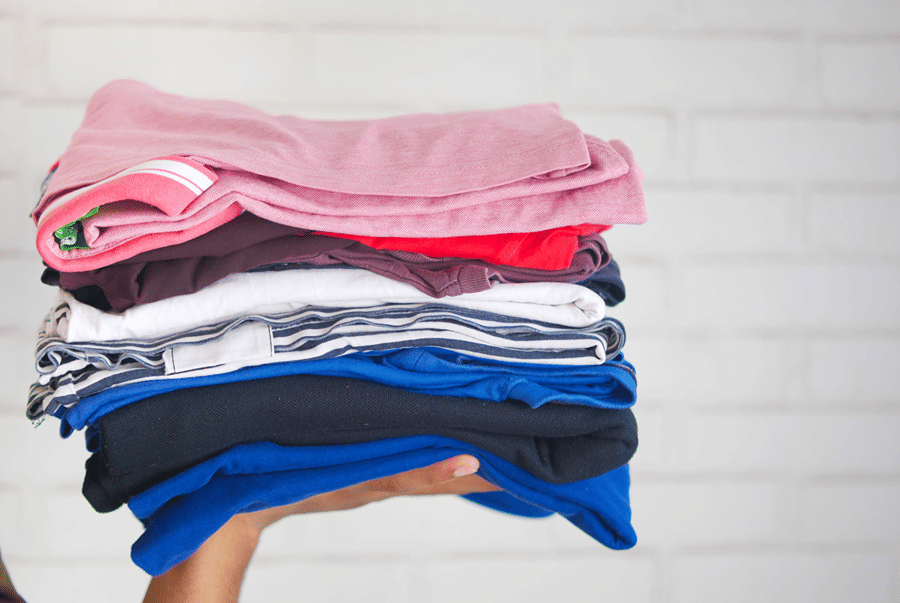 A hand holding a stack of freshly folded clothes
