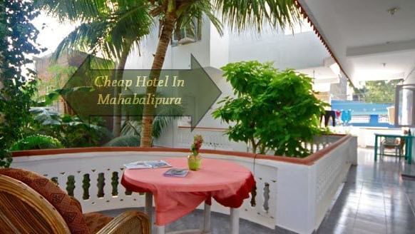 An outdoor patio with multiple chairs, a table, and plants beside palm trees, with 'Cheap Hotels in Mahabalipura' written on it.