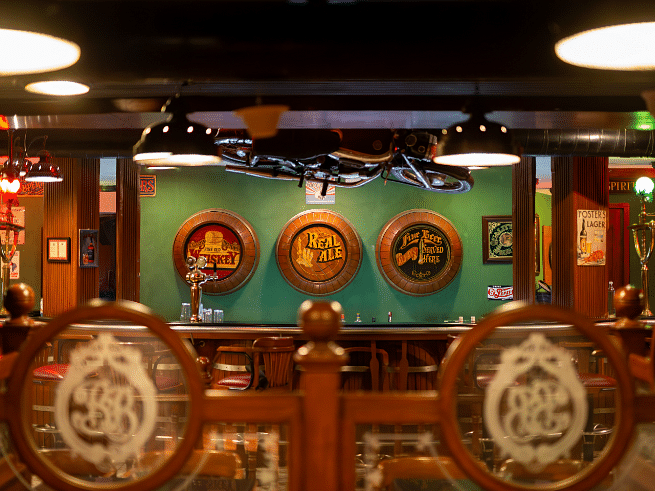 A dimly lit bar with a wooden bar counter, beer taps, and sports memorabilia on the walls.