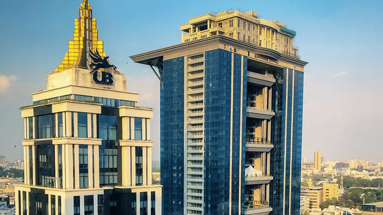 Modern high-rise commercial towers featuring glass windows and unique roof structures stand together against the skyline at UB City Mall.