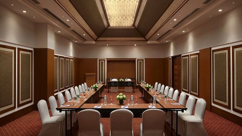 A sophisticated conference room setup with a U-shaped table arrangement, surrounded by elegant chairs, perfect for business meetings and presentations.