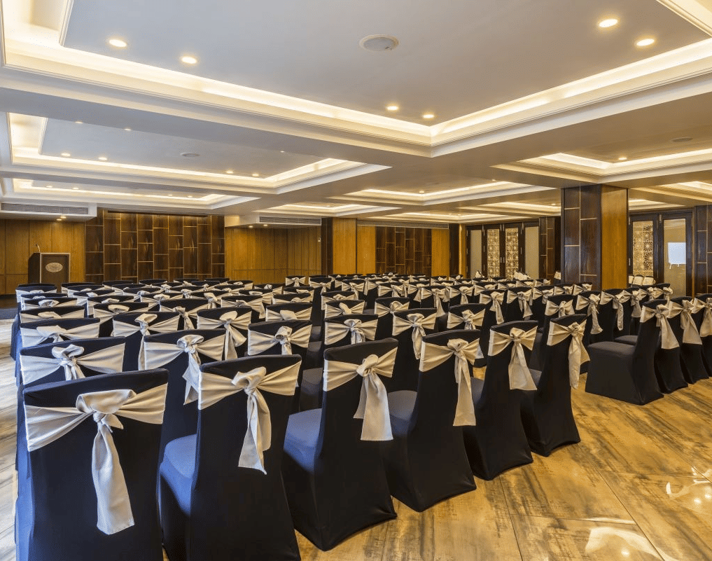 A large conference hall with warm lighting and rows of chairs facing the podium - The Citrine, Bangalore