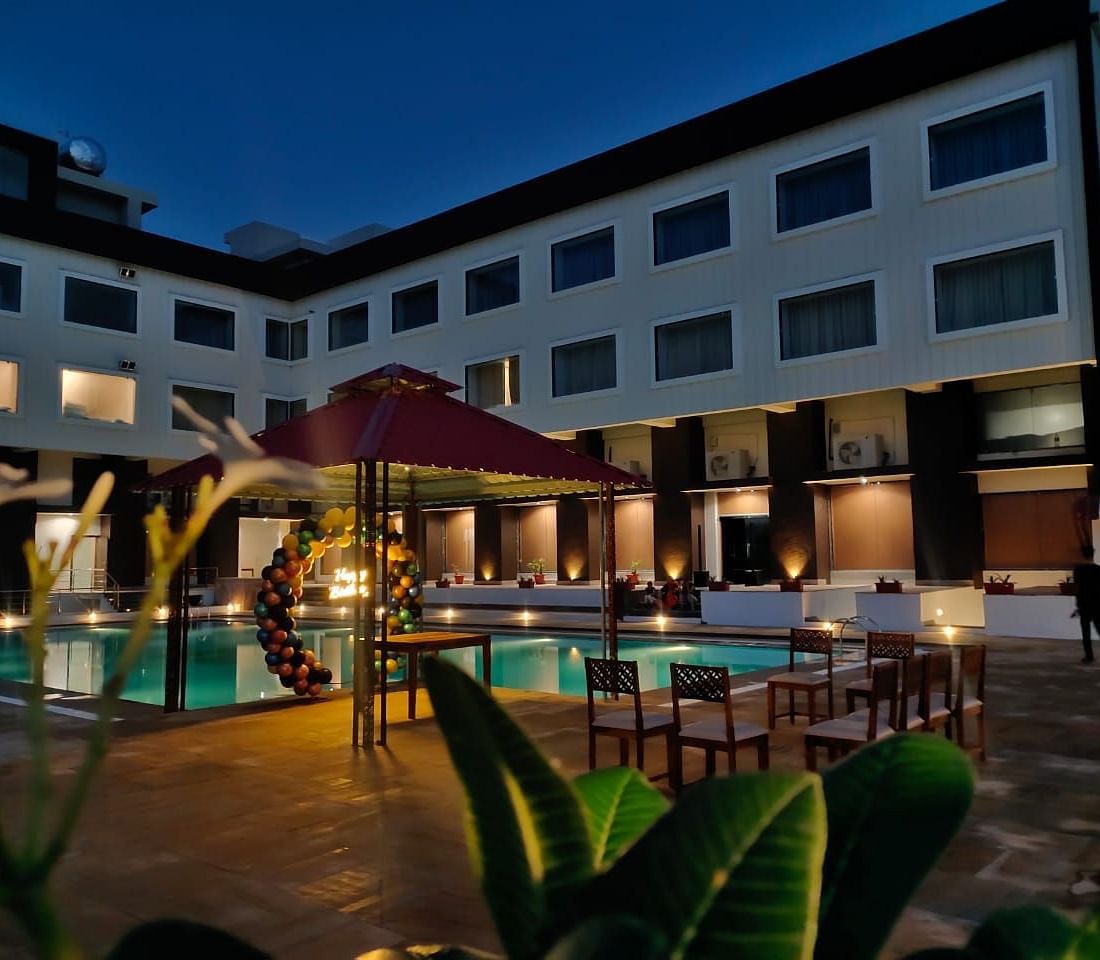 An evening view of a resort building with illuminated windows surrounding a swimming pool - Bamboo Saa Mulberry Resort, Pushkar