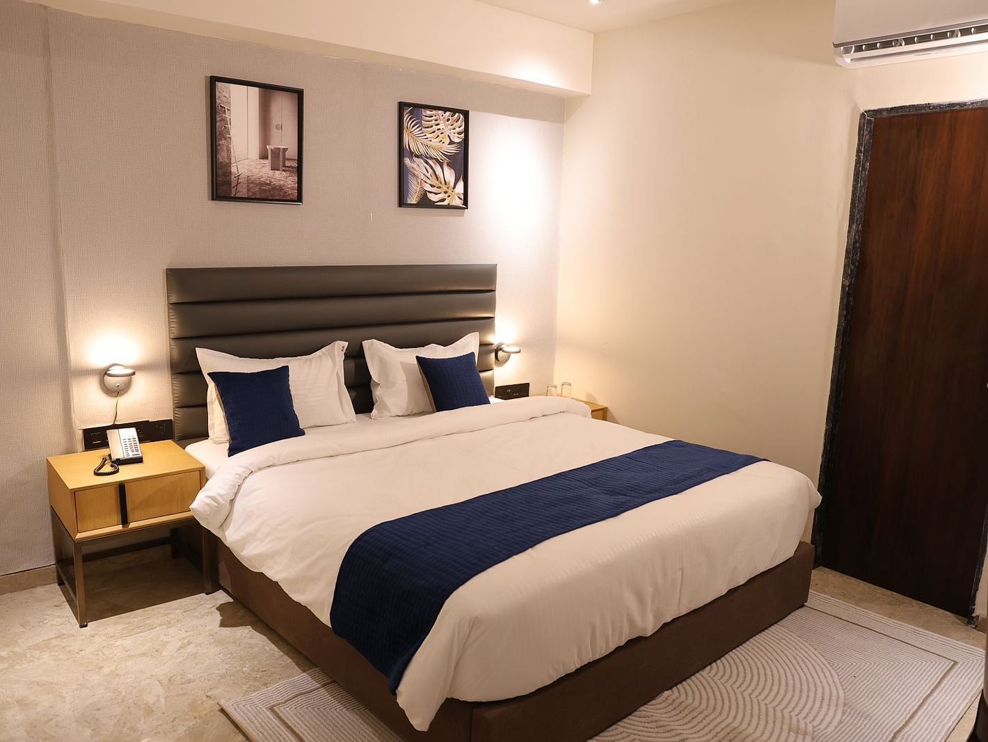 A stylish bedroom at Lords Eco inn Jamnagar Maheshwari Nagar with a large bed two bedside tables and artwork.