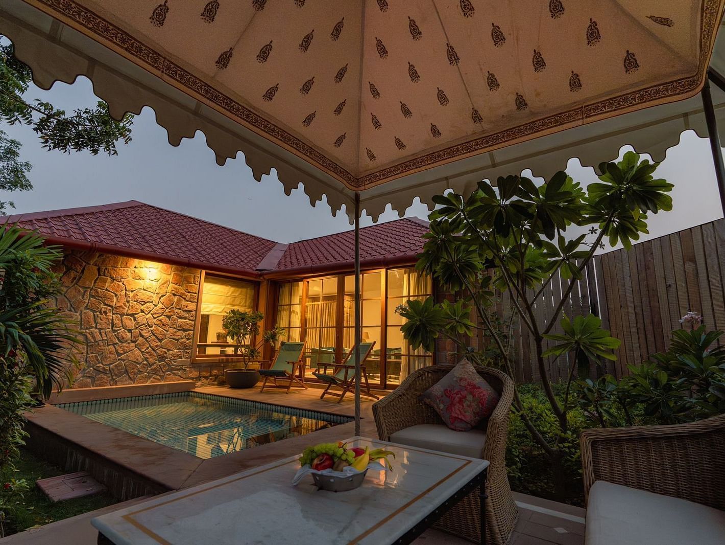 An outdoor seating area with a swimming pool in the corner at Surpura Bagh.