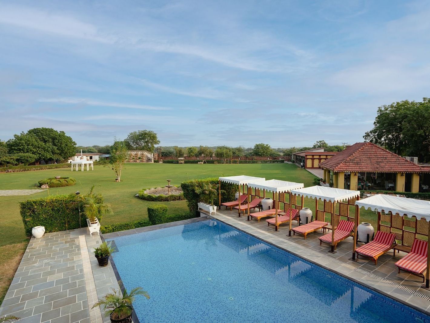 Aerial view of a swimming pool with lounge chairs on the side at Surpura Bagh.