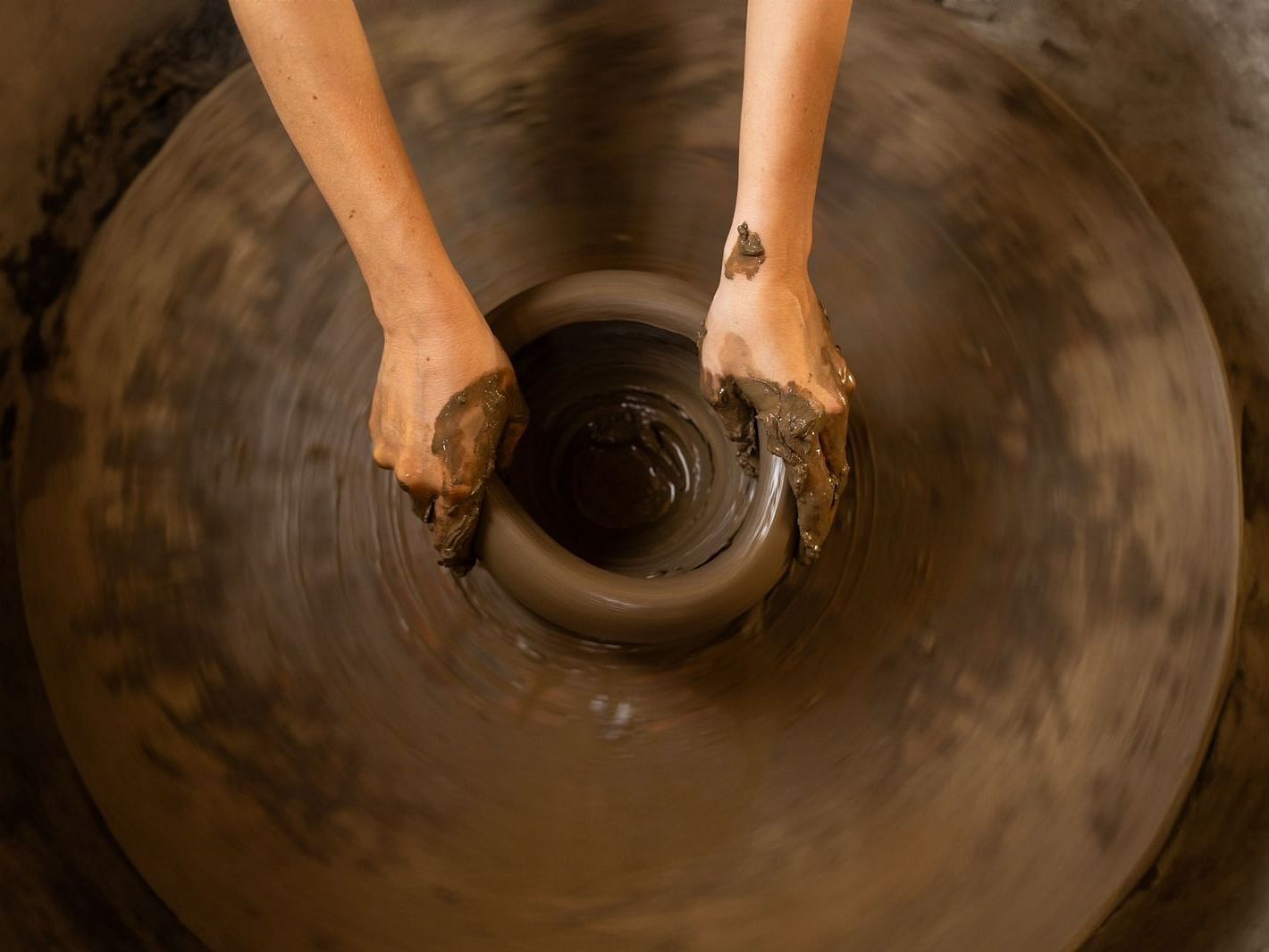 Top view of a hand moulding clay on a wheel at Surpura Bagh.