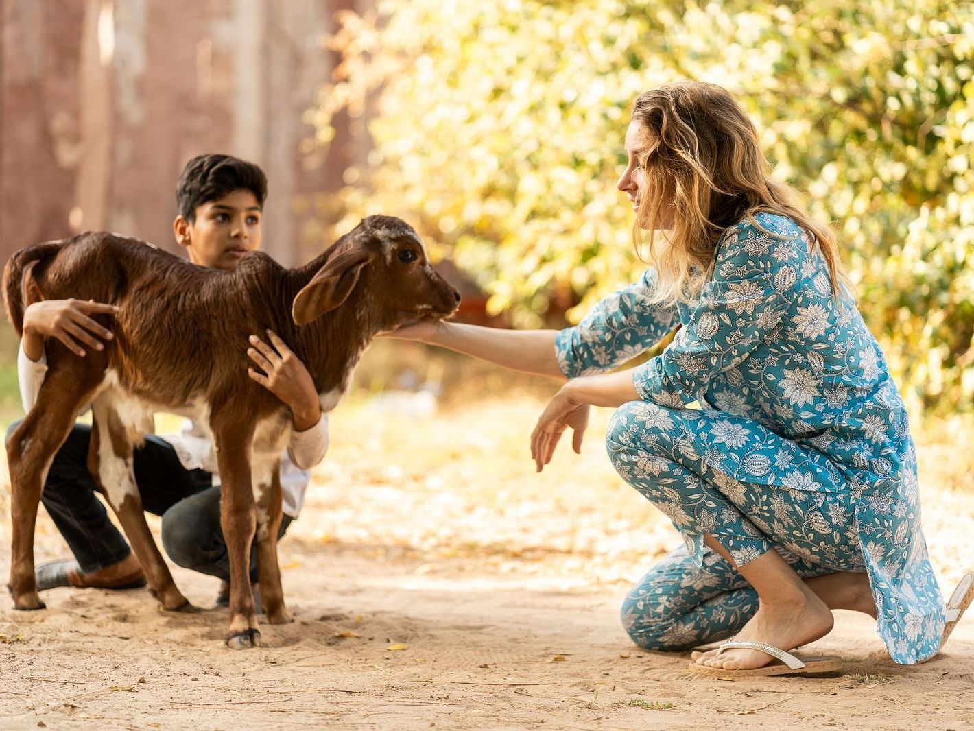 A woman petting goat as a boy holds it.