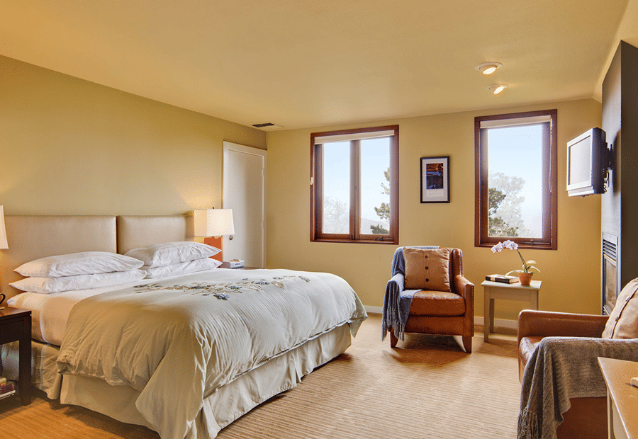 A large hotel room with a bed, seating area, and window.