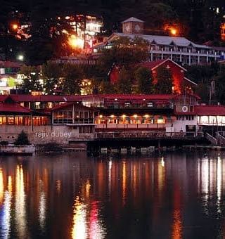 An image of a boat house floating at a lake with a backdrop image of lit houses 
