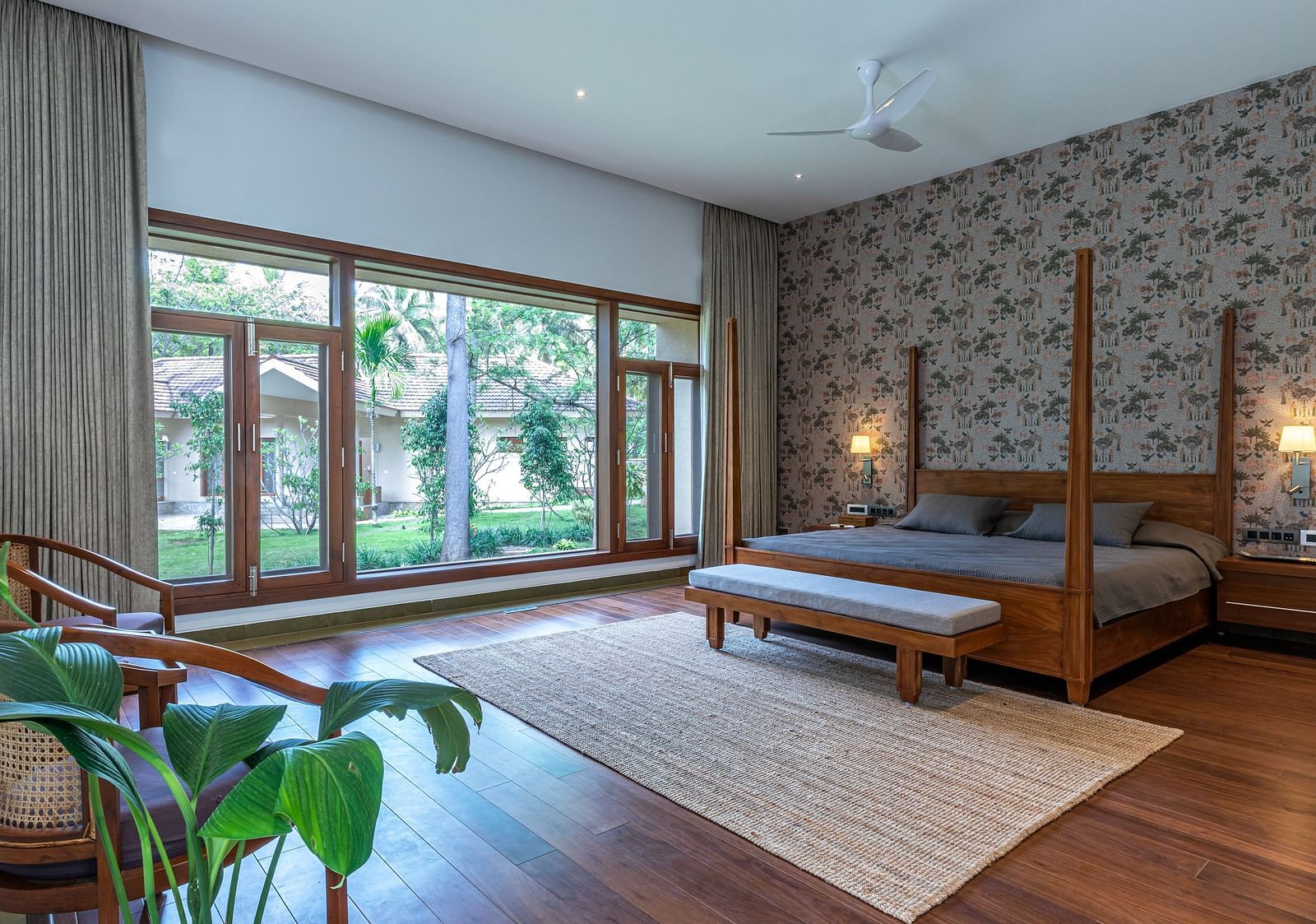 Bedroom with wooden furniture, large windows, rug, indoor plants, natural light at Shreyas Retreat