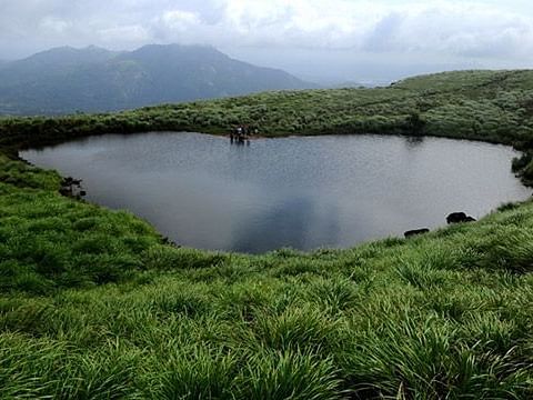 Serene lake nestled among lush green mountains and hills.