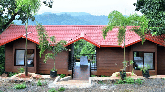 Riverview Luxury Cabin Exterior - Twin red-roofed wooden cabins in a forest setting with a mountain backdrop.