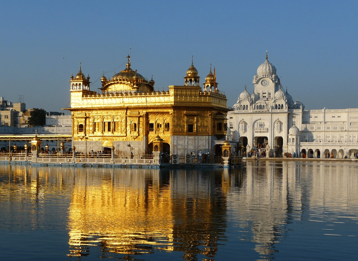 The Golden Temple, with its gilded upper structure brightly illuminated and reflected in the surrounding Amrit Sarovar