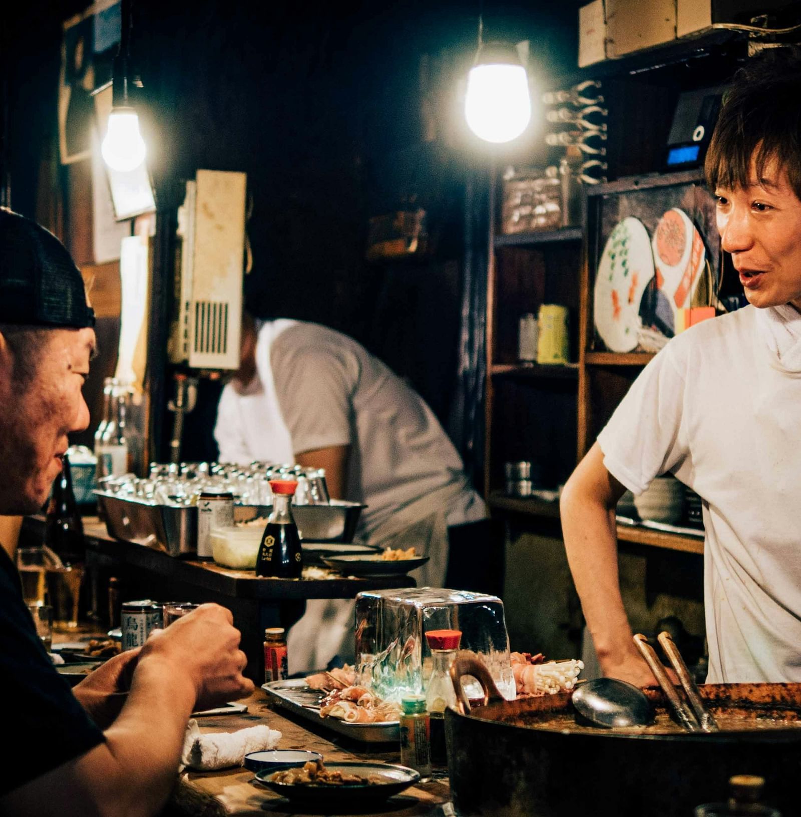 A chef in a stall with delicacies laid on a table