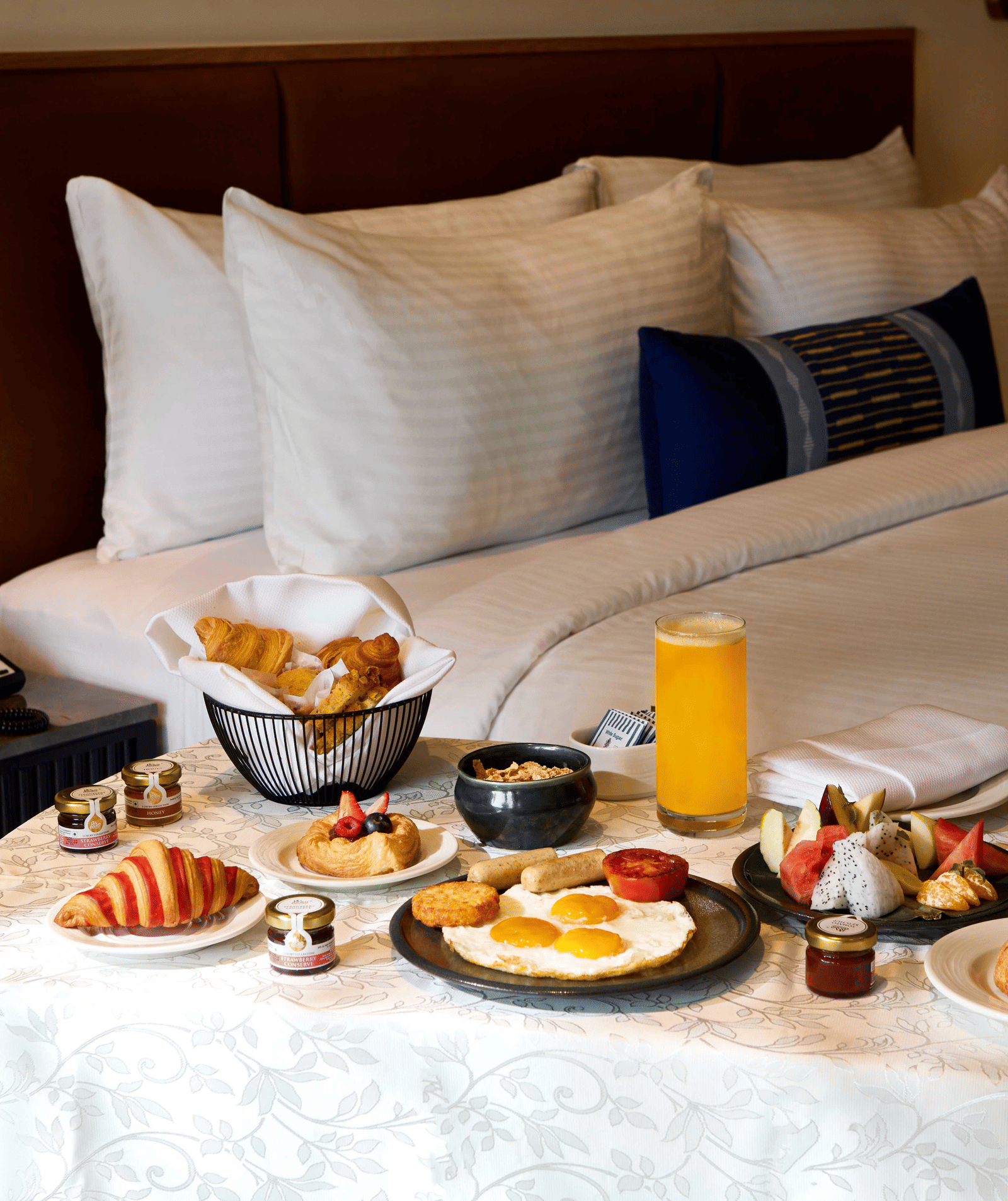 warmly lit bedroom with a Breakfast table beside a bed. 