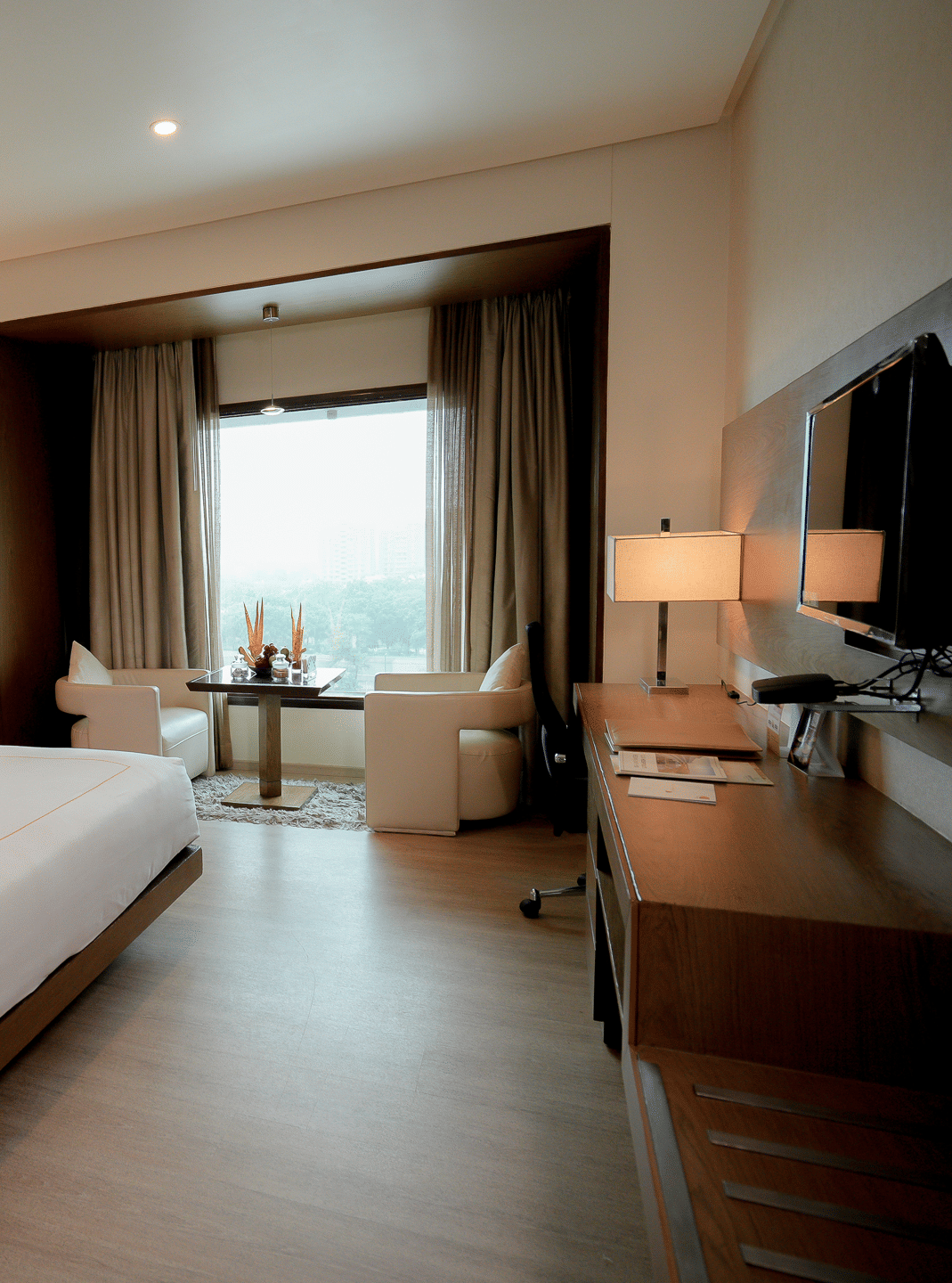 Spacious guest room with large bed, seating area, and a TV setup – Narayani Heights Hotel & Resorts