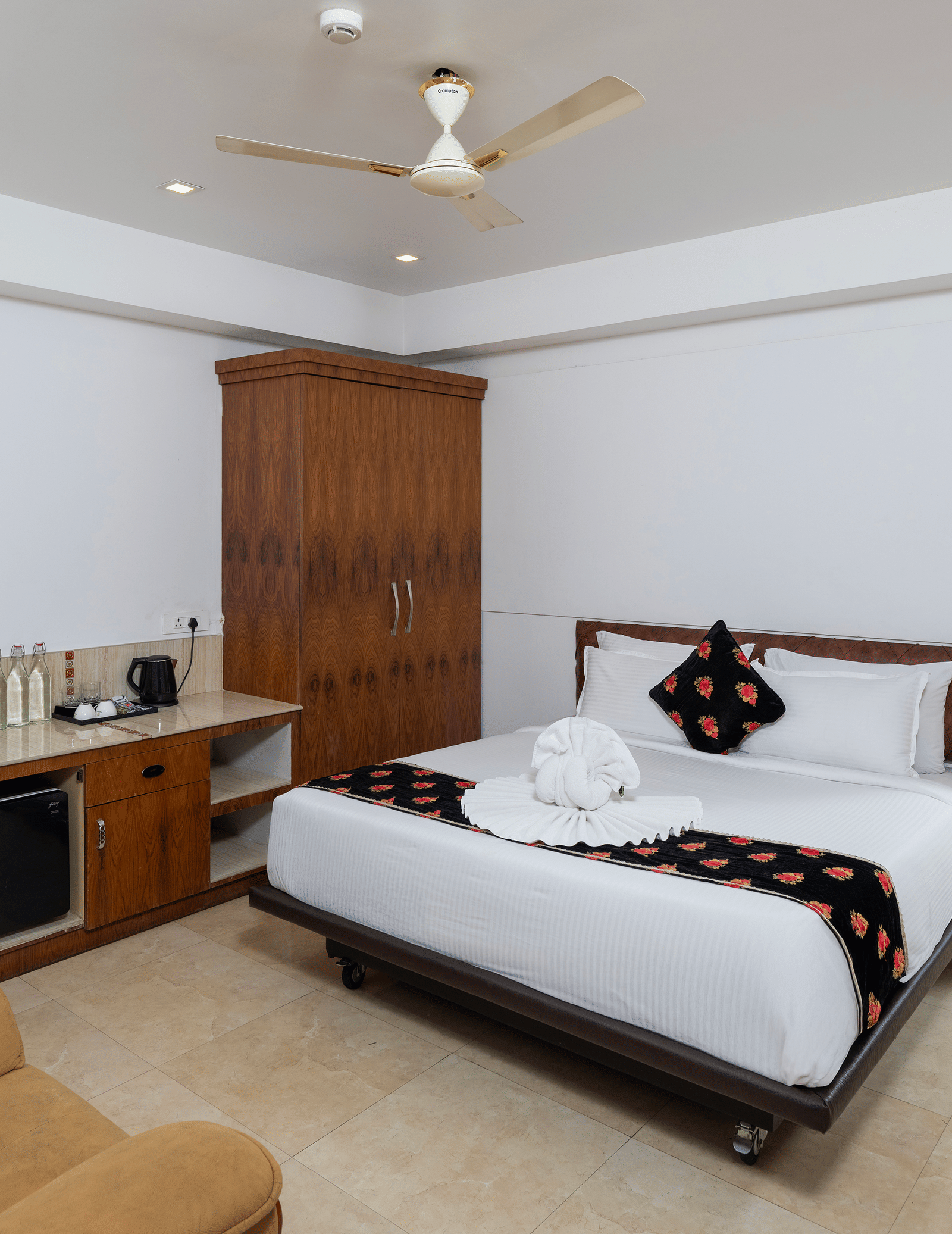 A bedroom in Family Interconnected Club Suite at Parakkat Nature Hotel and Resorts, Munnar with a double bed, a ceiling fan, a single-seating sofa, and an opening to another room.