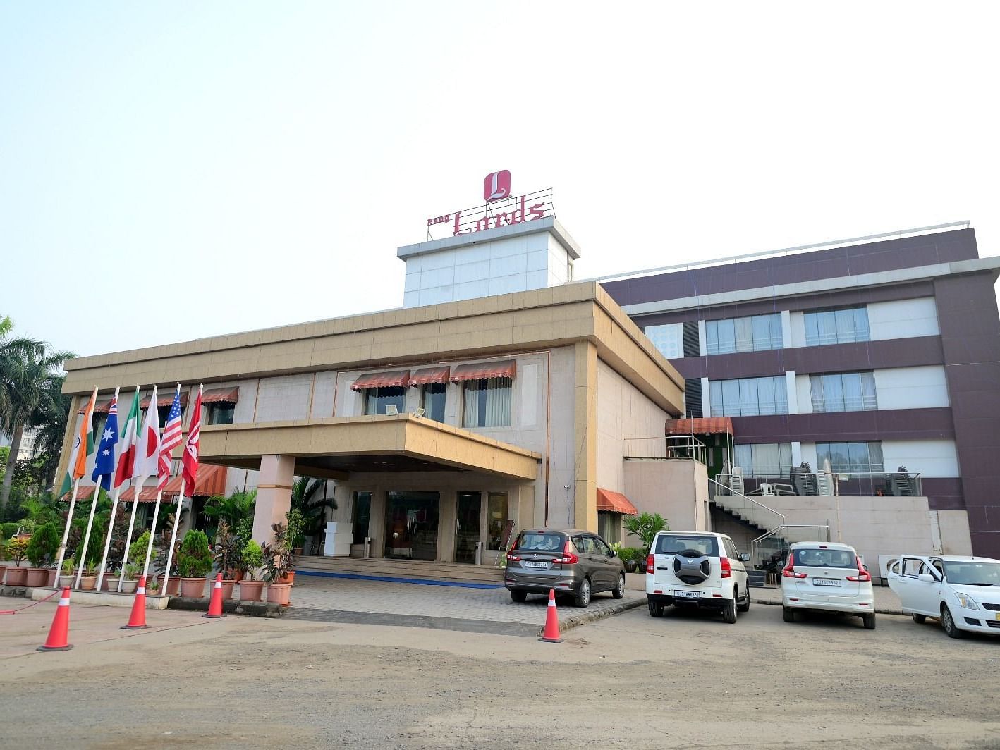 Facade of Rang Lords Inn, Bharuch, with its distinctive architecture, entrance, and parked vehicles on a bright day