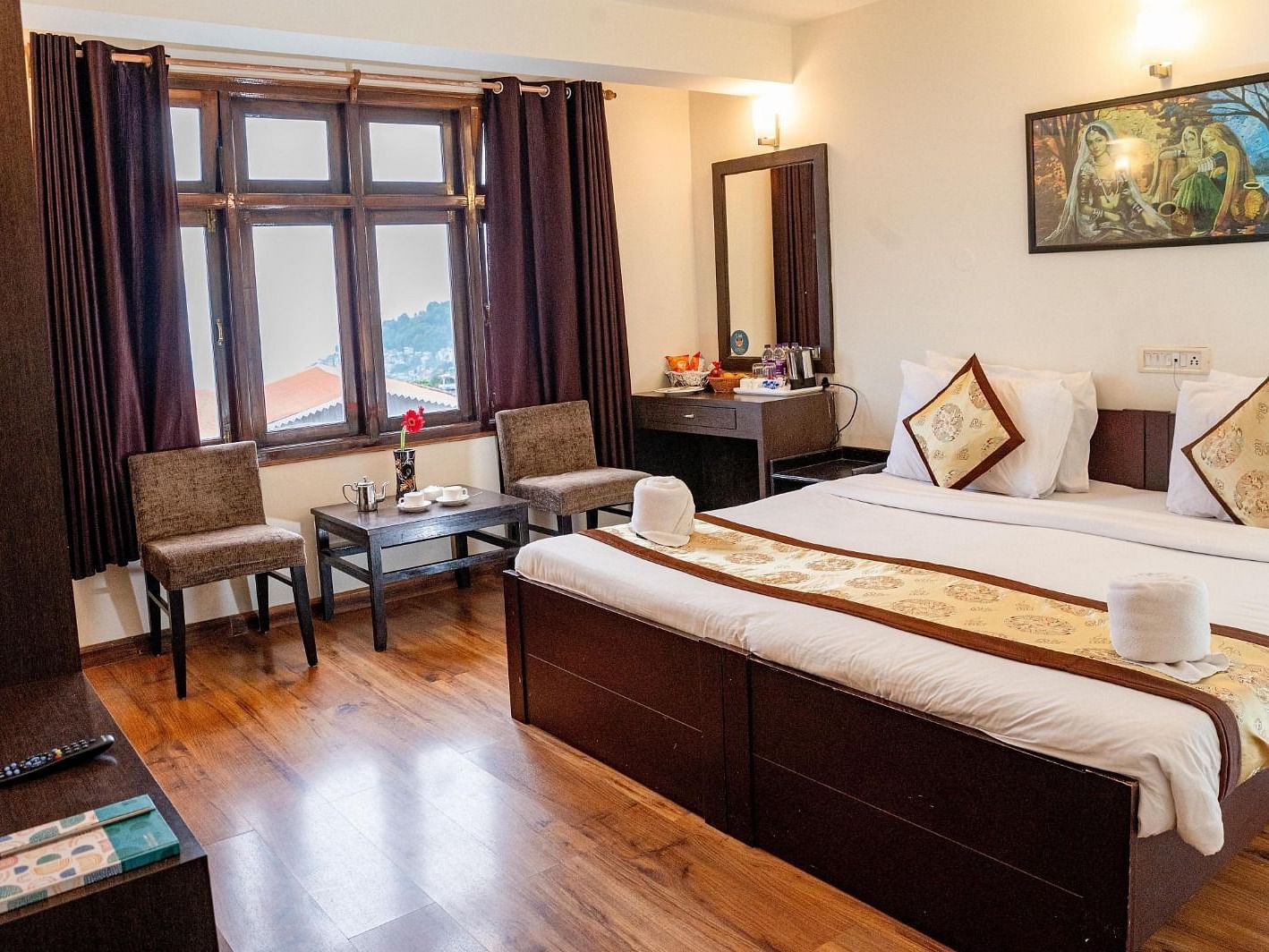A Premium Room featuring a double bed along with two arm chairs placed in front of a window at Sumitel Sanderling.