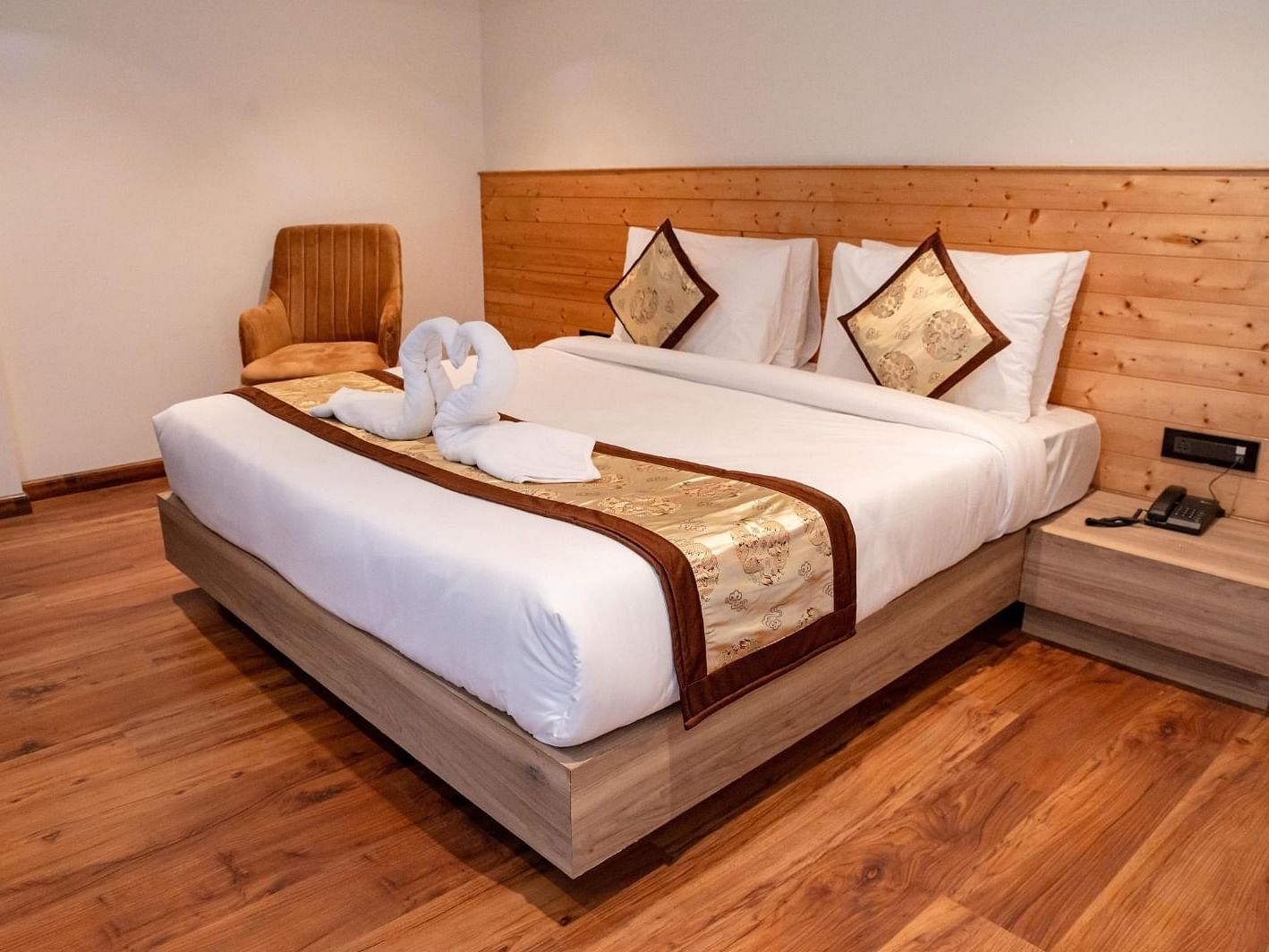 A cosy double bed with swans made of white towels kept on the bed runner in Standard Room at Sumitel Sanderling.