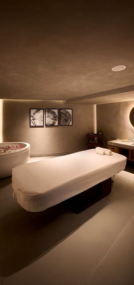 Corner view of the spa bed with a back-lit circular mirror at the far end of the room at our nature resort near Mumbai.