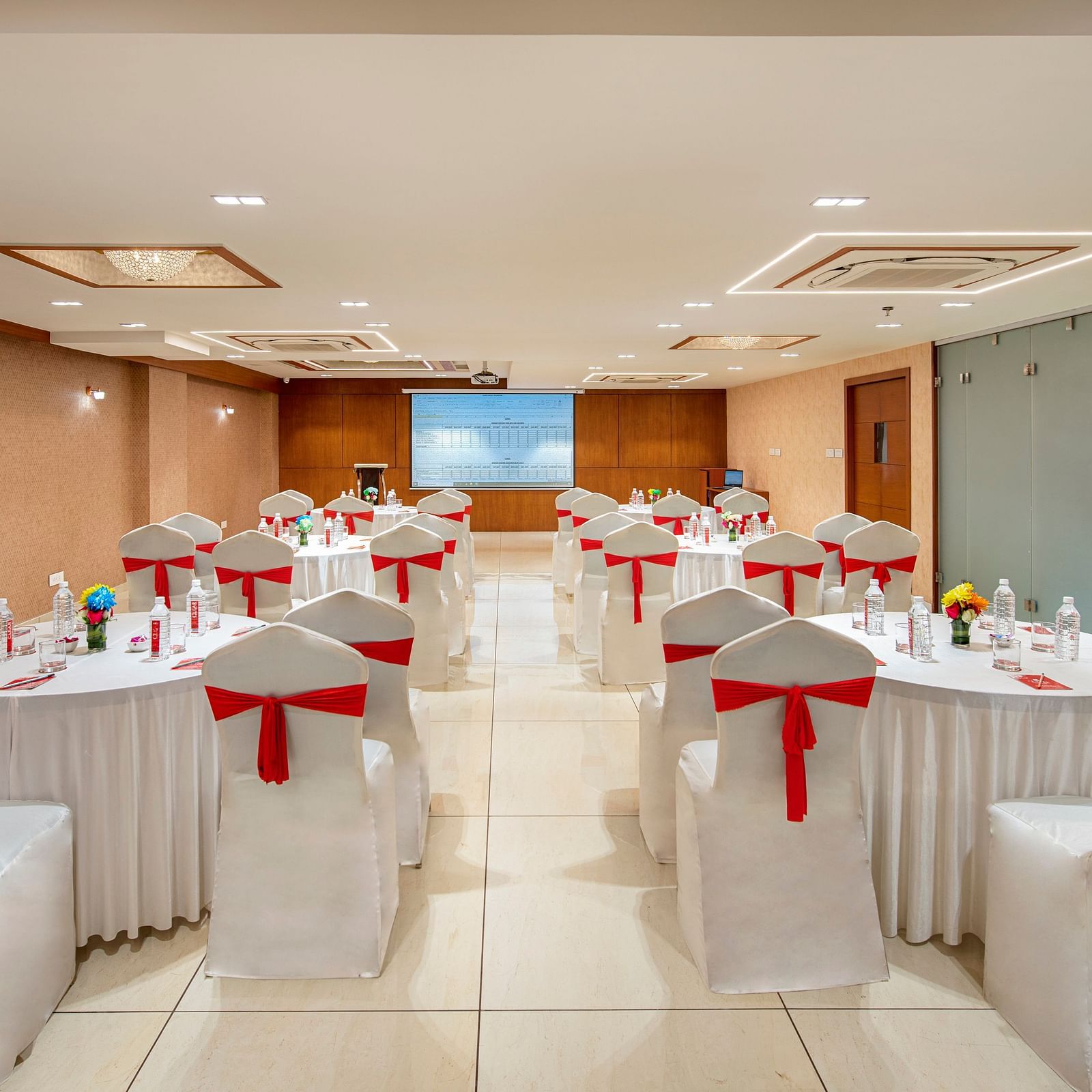 A banquet hall with round tables elegantly set for a formal occasion, likely a wedding or reception - SK Lords Inn Ahmedabad