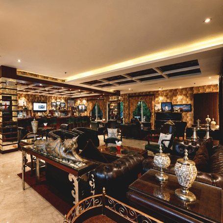 Lighthouse Bar with a wooden counter, green stools, leather sofas, brass lamps and lighthouse-themed wall art at MAYFAIR Palm Beach Resort, Gopalpur-on-Sea.