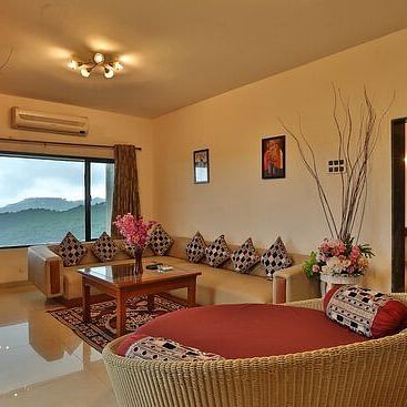 Image of living room of  a Pent House with a large window and spacious sofas - Camel Valley Resort, Igatpuri