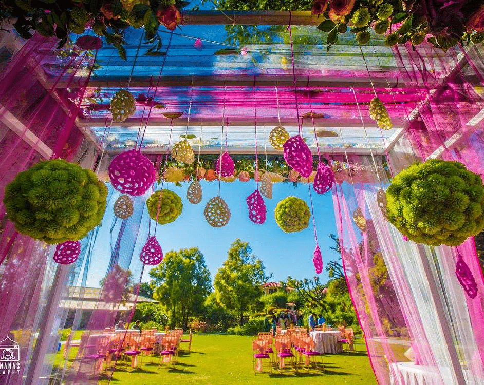 Indoor wedding venue with a colorful ceiling and hanging decorations.