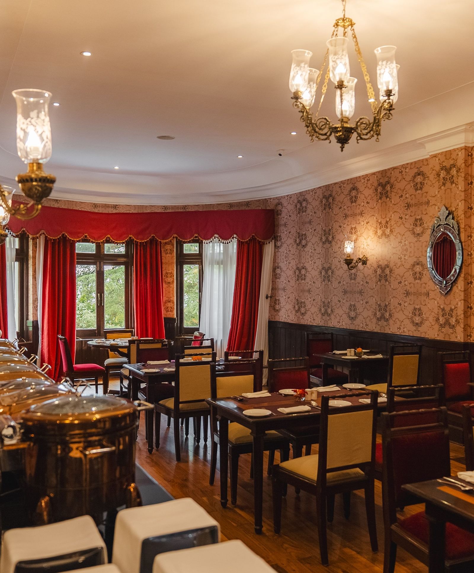 A refined dining room with well-arranged tables and chairs, accented by a chandelier and rich decorative elements.