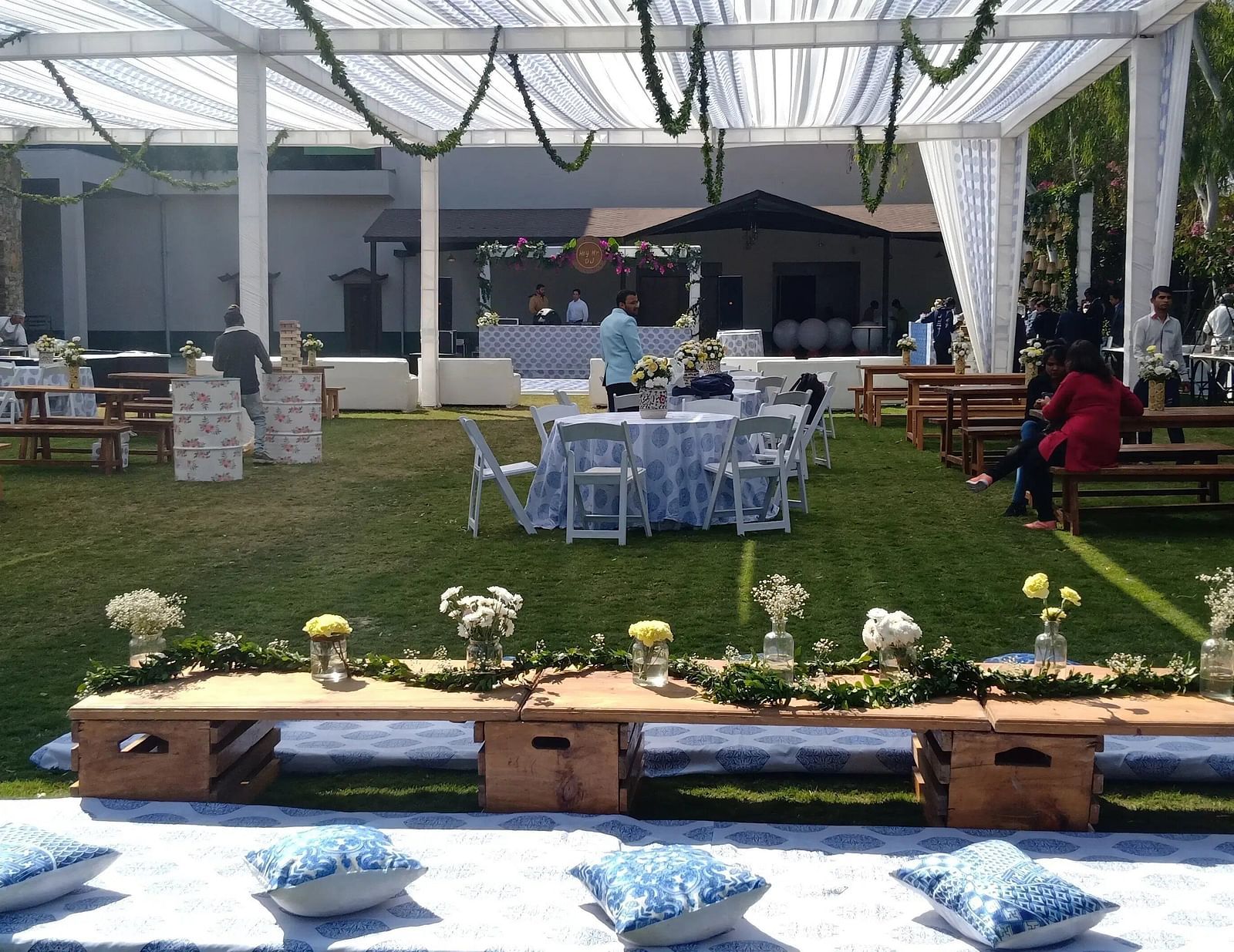 Outdoor event setup with a tent, tables, chairs, and decorations on a lawn. - Bamboo Saa, Udaipur