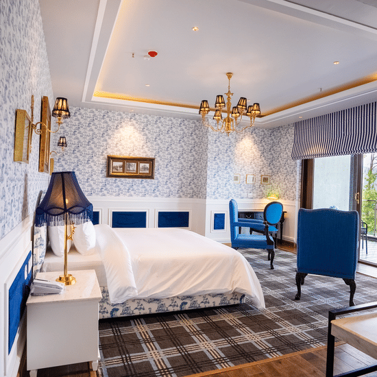A hotel room with a large bed and comfy blue chairs  - The Manor Luxury Hotel, Shimla