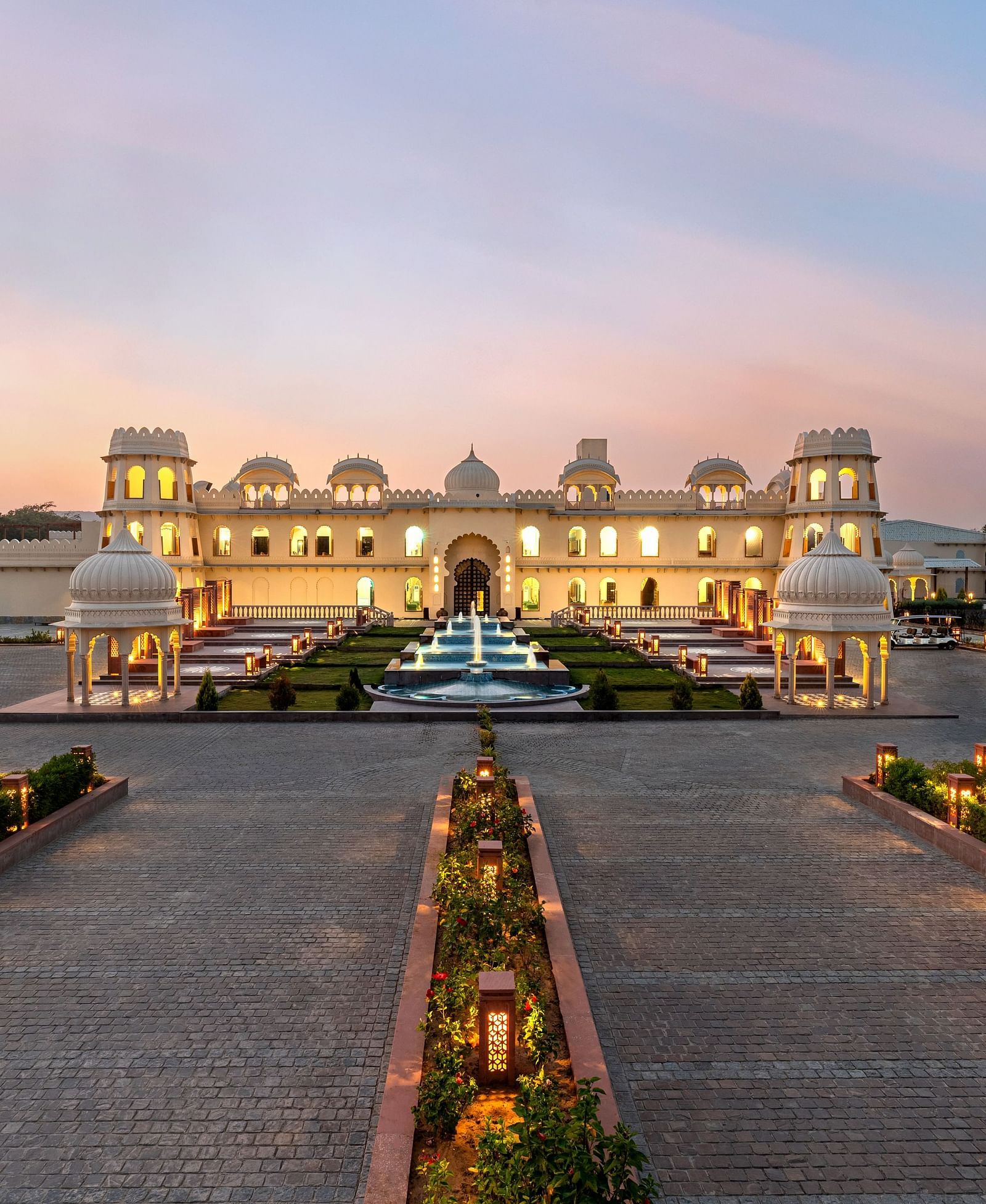 Exterior view of Kesar Bagh Palace building at sunset with landscaped pathways.