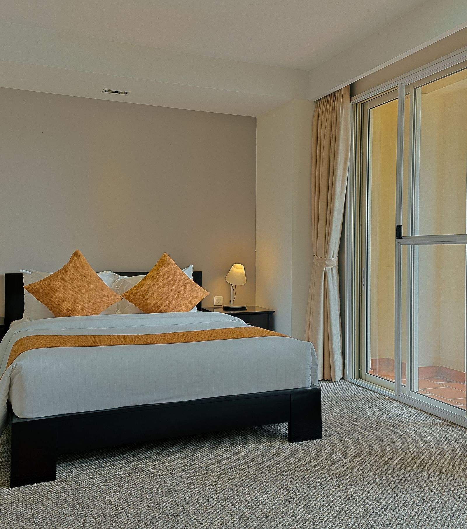 A bedroom with a bed, nightstand, and curtains | Penthouse | Central Mansions, Phnom Penh