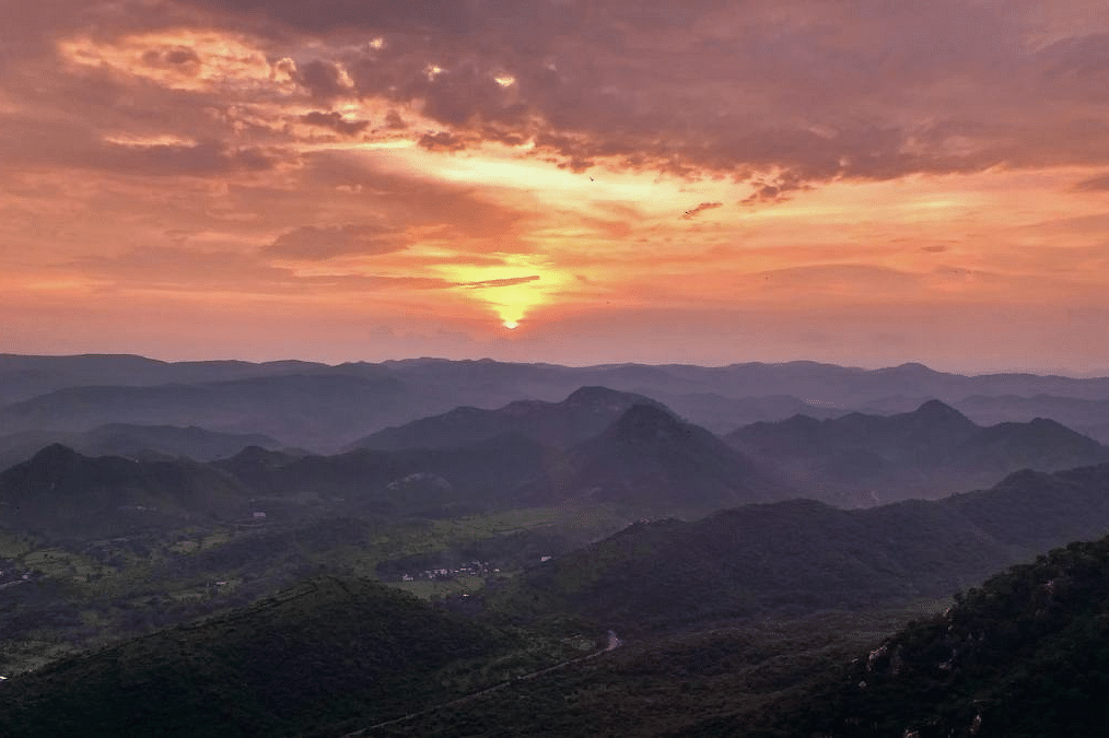 Sunset over layered hills with a landscape view.