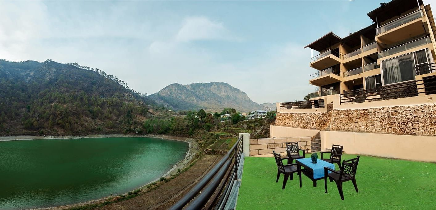 Table and chairs facing a serene green lake and forested hills.