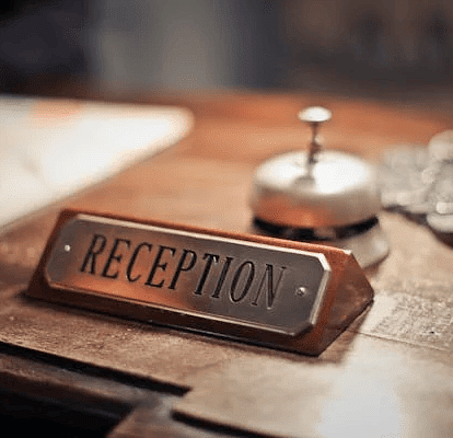 A photo of a table featuring a nameplate of reciption and a bell on it.