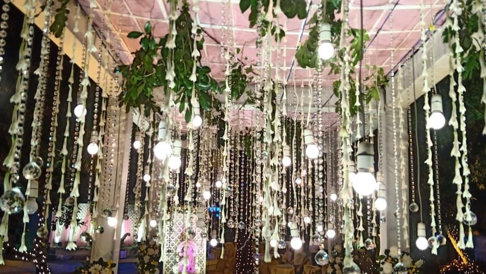 An indoor space is adorned with numerous hanging floral strings and lights, creating a festive and ethereal ambience