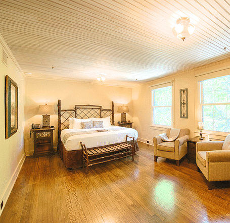 corner view image of a spacious bedroom featuring a common seating area along with a comfortable double bed - Historic Tapoco Lodge