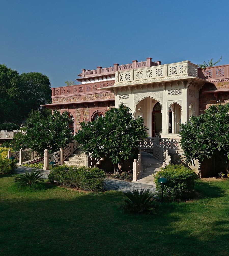 A traditional Indian palace or large building with lush gardens under a clear sky - Khas Bagh, Jaipur.