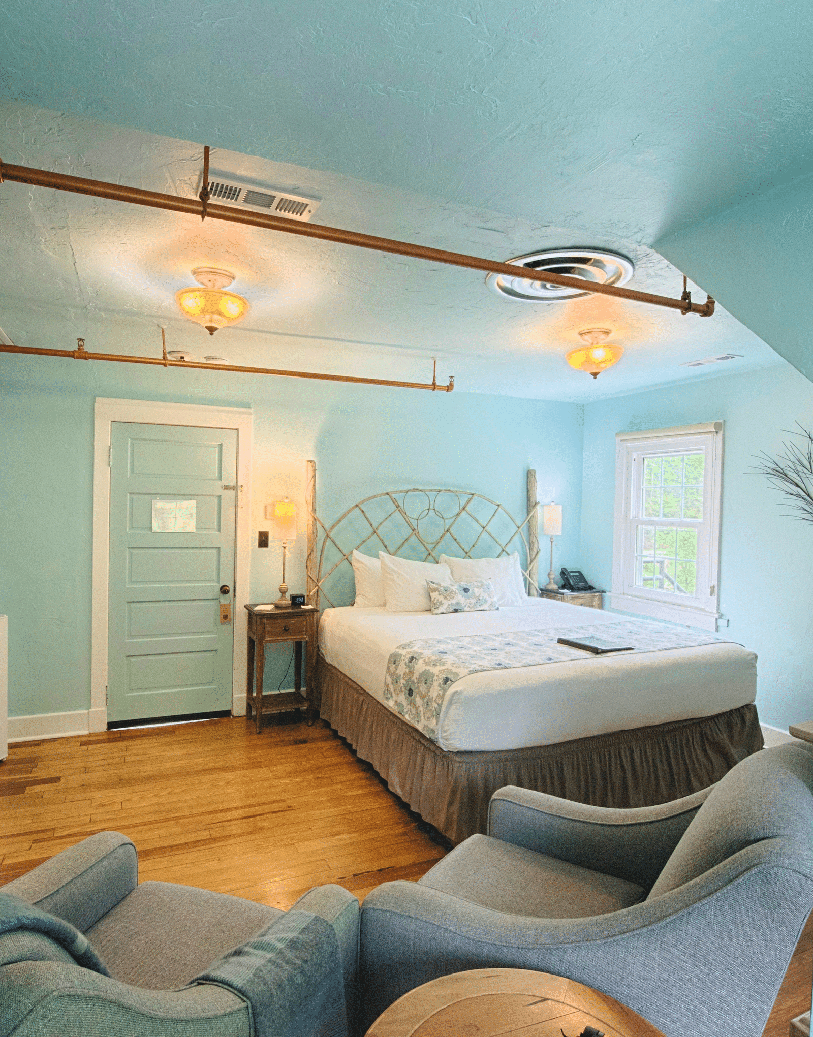 a beautiful room with calming tones featuring a double bed and a mini refrigerator in the room - Historic Tapoco Lodge