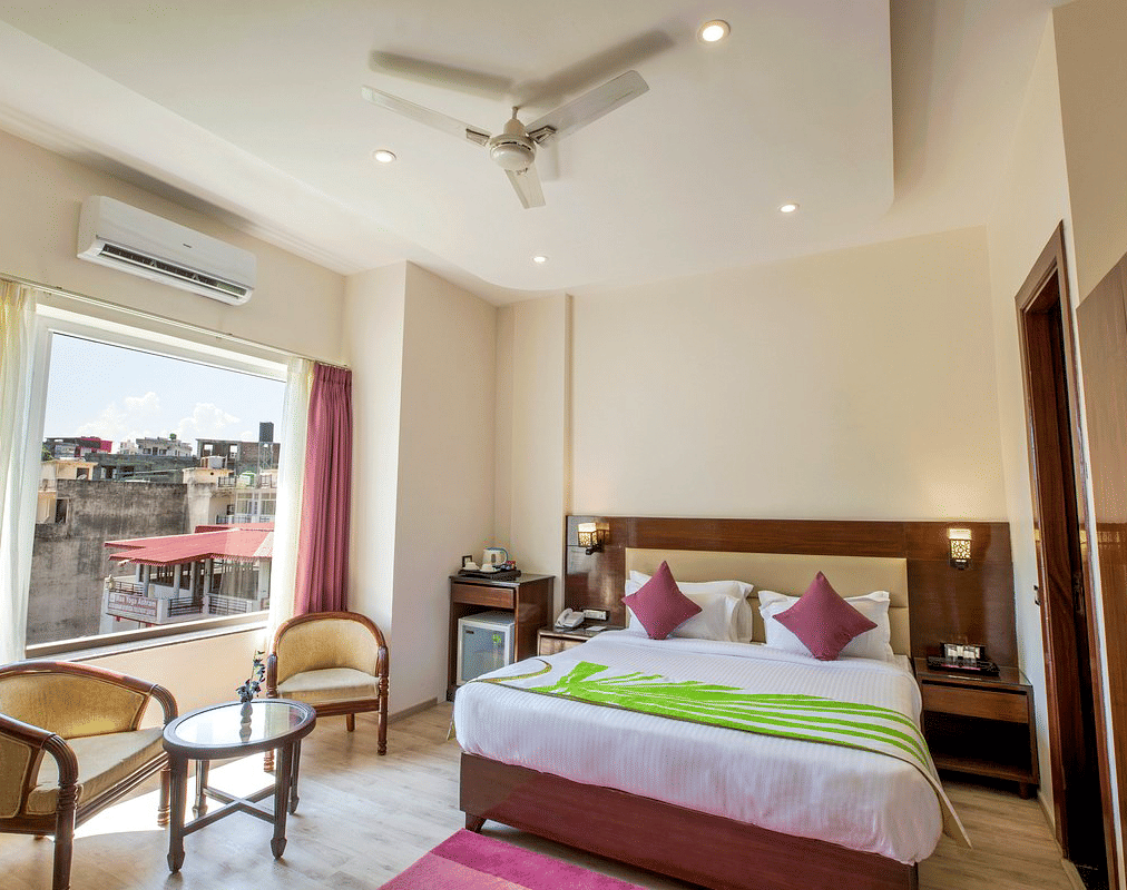 Full view shot of the Deluxe room featuring a double bed along with beautiful city views from the window at DLS Hotels On The Ganges.