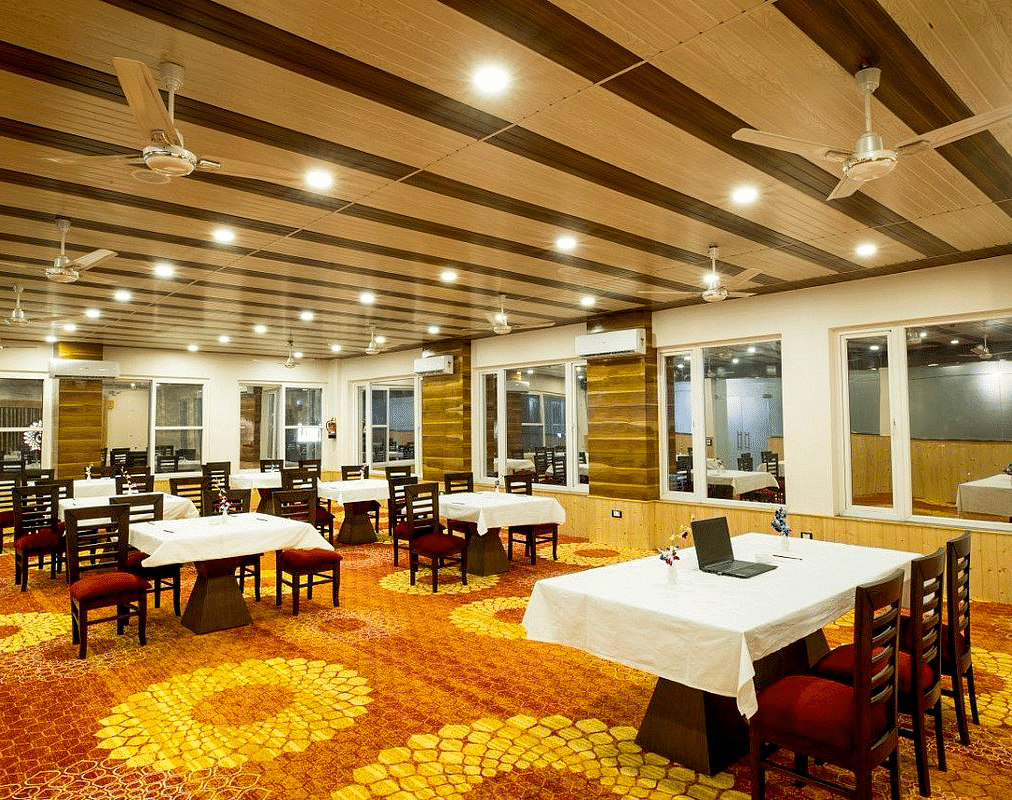 Corner view shot of the banquet hall at Regenta Inn DLS with panel lights and ceiling fans attached on the ceiling.