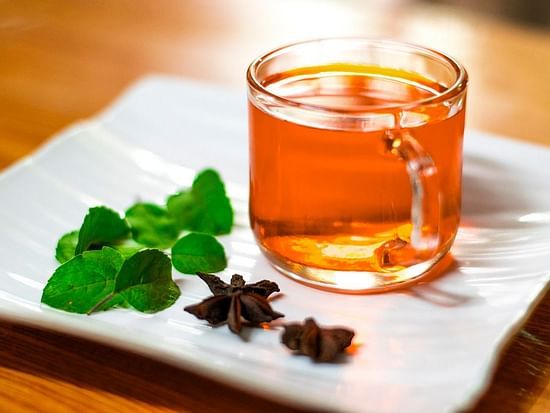 Aromatic herbal tea served in a clear glass cup, accompanied by fresh mint leaves and star anise, offering a soothing and rejuvenating Ayurvedic wellness experience.
