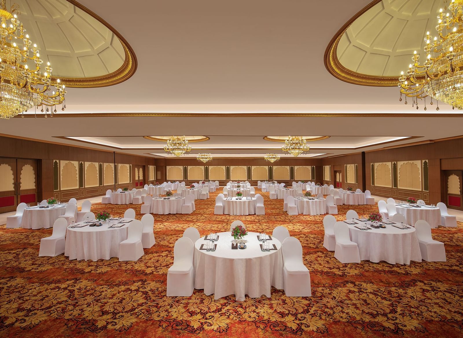 A banquet hall in Mahabalipuram with chandeliers, carpeted floors, and a cluster-type seating arrangement – Kaldan Samudra Palace, a Beautiful Wedding Venue ECR