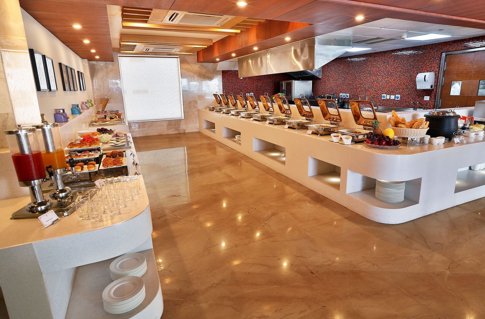 A restaurant with elegant interiors and bright lighting featuring the buffet counter with a wide array of dishes served - Ramada by Wyndham, Ghaziabad, Vasundhara