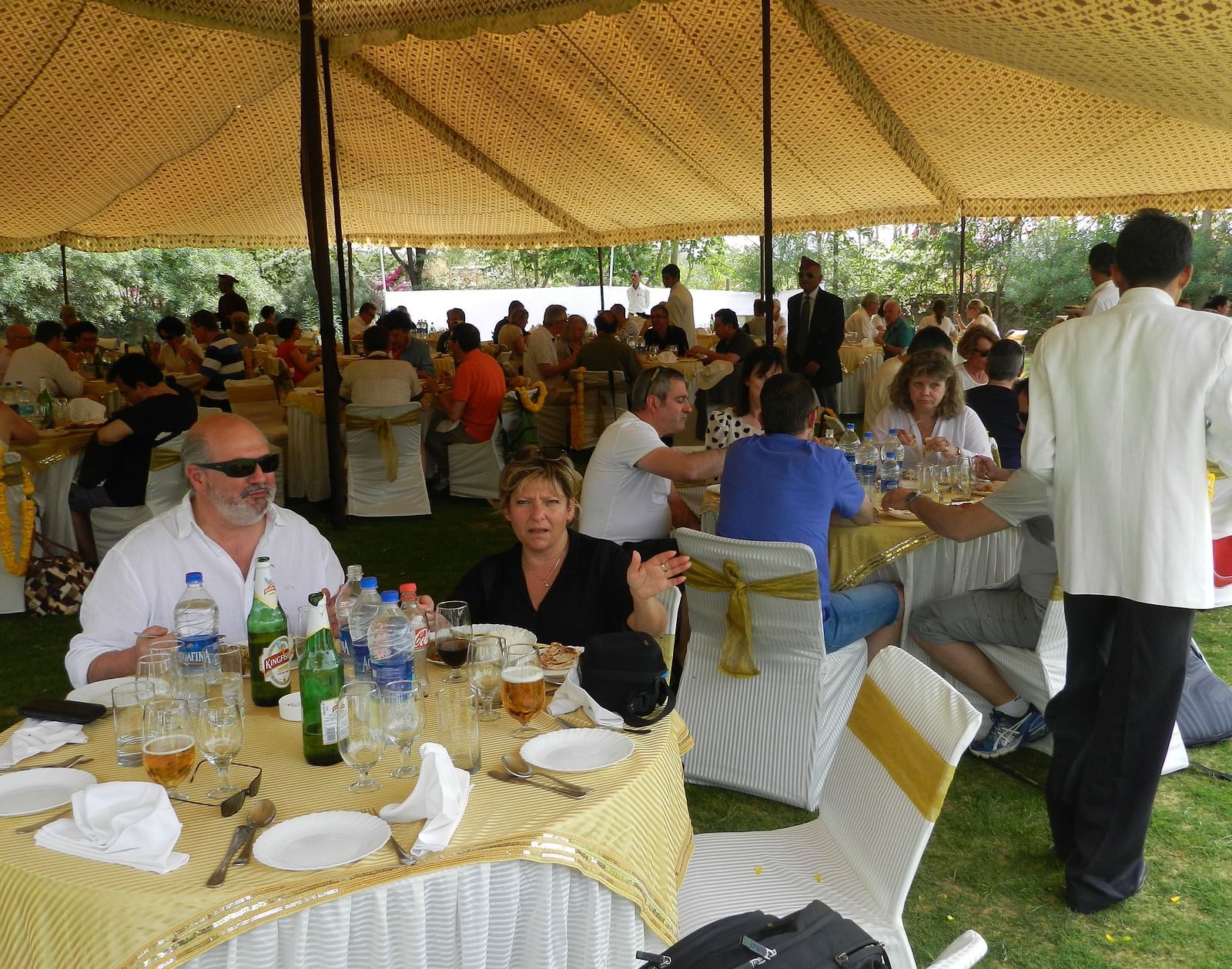 A lively outdoor gathering under a tent, where guests dine and chat in a festive atmosphere - Khas Bagh, Jaipur.