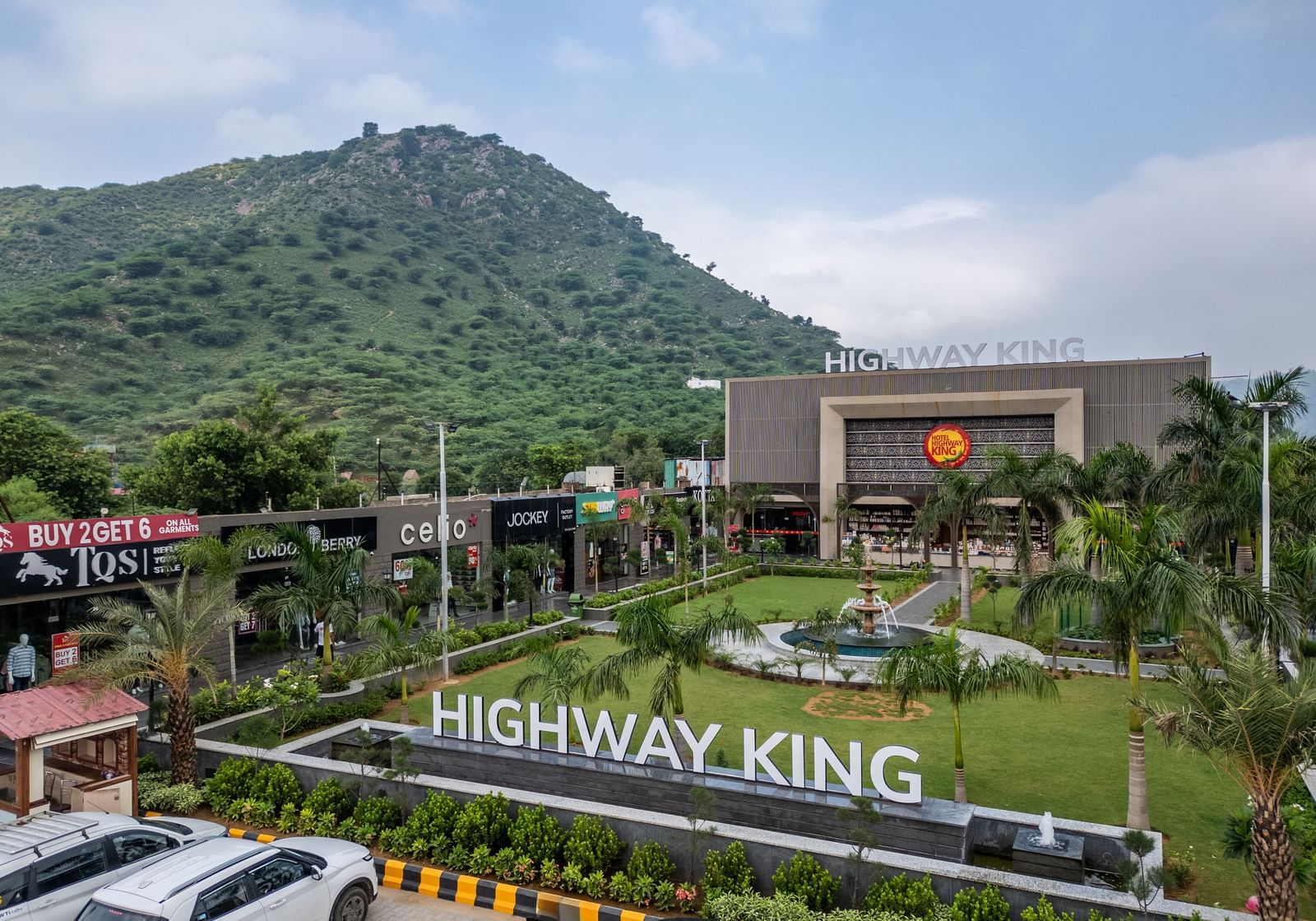 Wide view of the hotel complex, large entry sign, and surrounding vegetation at Hotel Highway King, Neelka.
