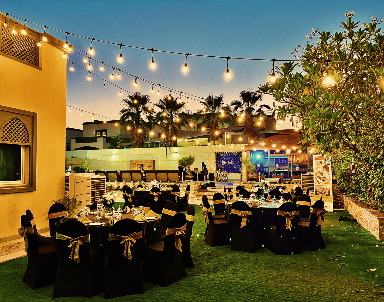 Outdoor dining setup with tables and chairs near greenery at Marco Polo Hotel.